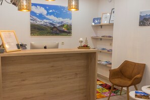 A reception desk with a wooden finish, a laptop, framed certificates, and a chair. - Fernerblick Apartments (Tux)