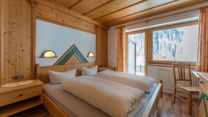 Une chambre dans une cabane en bois, avec deux lits, une chaise en bois et une vue sur les arbres par la fenêtre.