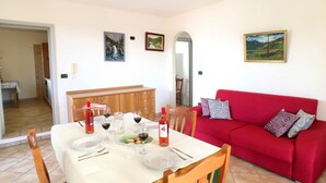 A dining area with a table set for two, a red sofa, and artwork on the walls. - Appartamento Apollo (Morciano di Leuca)