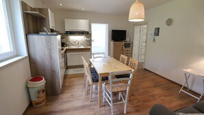 Eine moderne Küche mit weißen Schränken, einer Holz Arbeitsplatte und einem Essbereich mit Holztisch und weißen Stühlen.