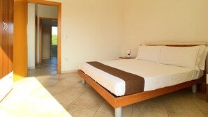 A bedroom with a bed, bedside table, and a view of a balcony. - Appartamento Emma (Gallipoli)