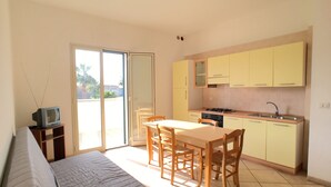 A compact living space with a kitchenette, a dining area, and a sofa. - Appartamento Emma (Gallipoli)