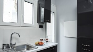 Une cuisine moderne dotée d’un évier en acier inoxydable, de meubles de rangement noirs et d’une fenêtre située au-dessus du plan de travail.