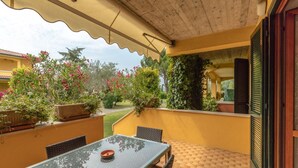 An outdoor patio with a glass table and chairs, surrounded by potted plants and a yellow wall. - Casa @rena - Pool - Patio - Pet friendly - LAKE (Sirmione)