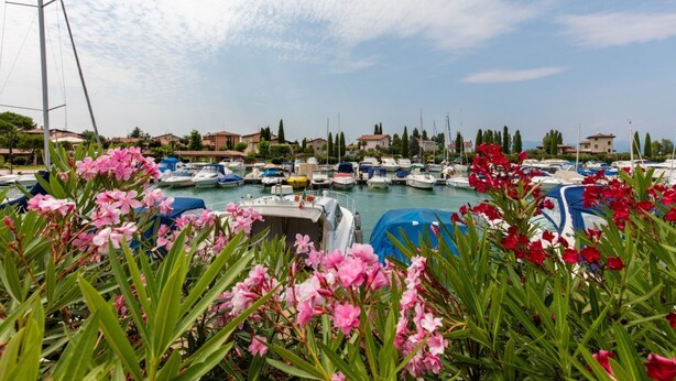 A marina with boats docked, surrounded by residential buildings and greenery. - Casa @rena - Pool - Patio - Pet friendly - LAKE (Sirmione)