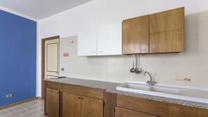 A kitchen with wooden cabinets, a granite countertop, and a white sink. - Margherita - Piano Ribassato (Taviano)