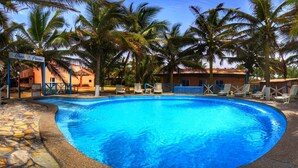 A swimming pool surrounded by palm trees and lounge chairs, with a building labeled "Oceo Piscine" in the background.