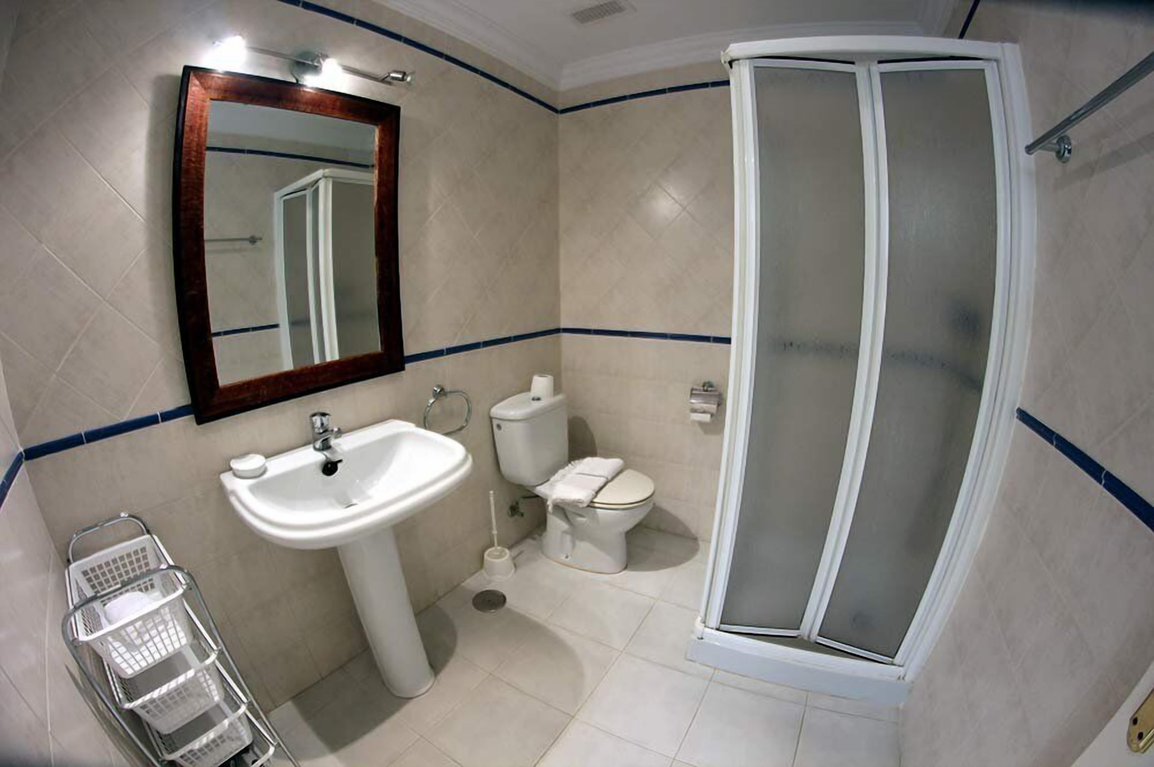 A bathroom with a white sink, toilet, and shower.