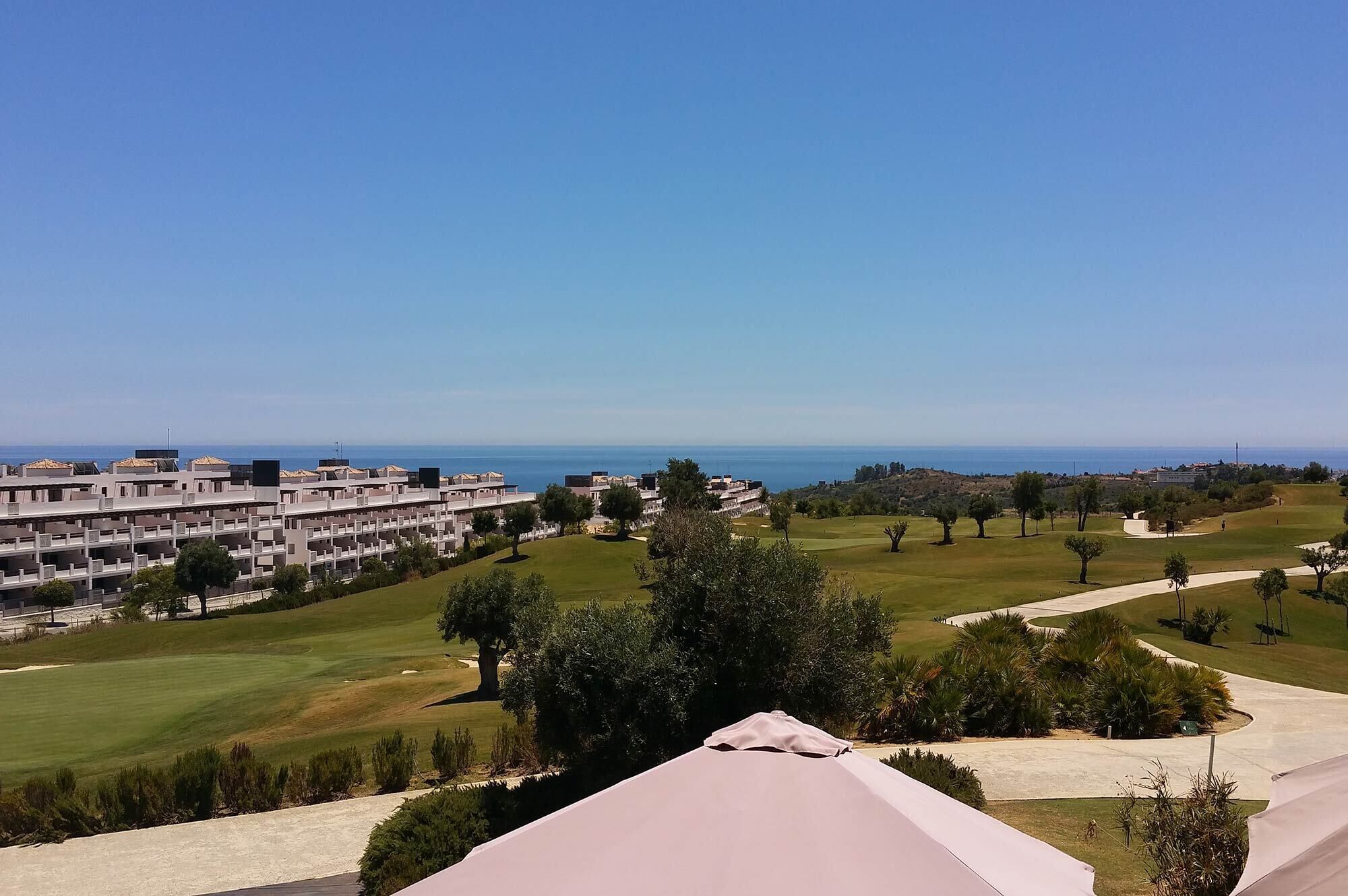 A resort with multiple buildings, a golf course, and a view of the sea.