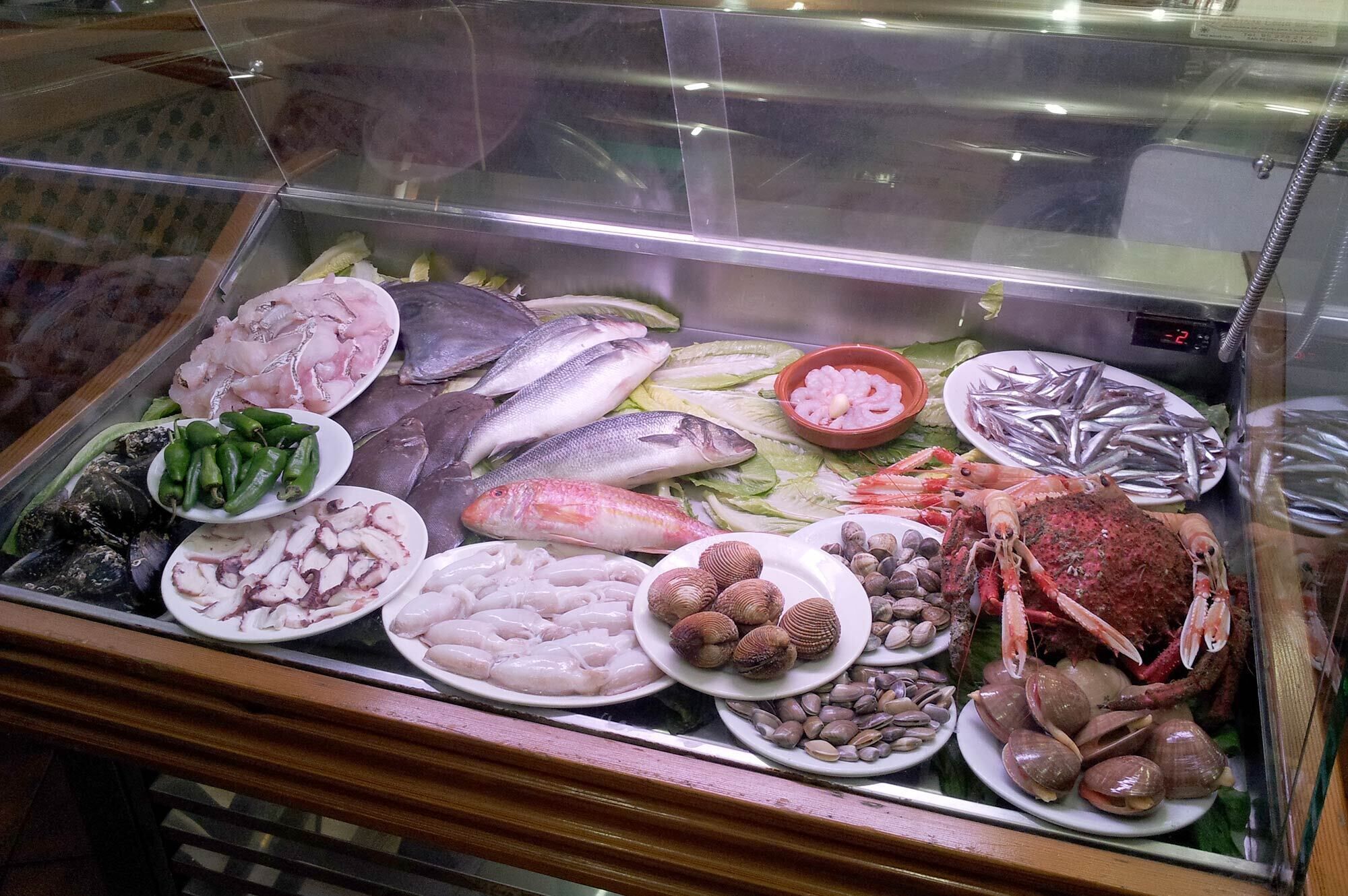 A seafood display case with various types of fish, shellfish, and shrimp.