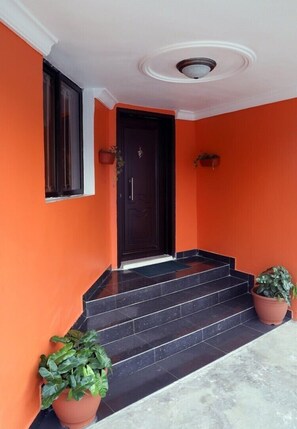 Stunning building entrance with a welcoming entrance, flanked by potted plants and a decorative ceiling.