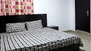 A bedroom with a bed, a nightstand, a black door, and an air conditioning unit on the wall.