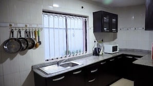 A kitchen with dark cabinets, a window with curtains, a sink, and a microwave.