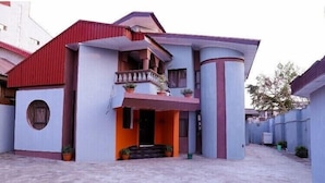 A two-story house with a balcony, a circular window, and a red roof.