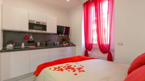 A modern bedroom with a bed, a red blanket, and rose petals. - notaMi - NotaMi Red Studio (Milan)