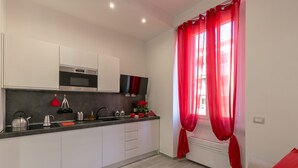 A modern kitchen with white cabinets, a built-in oven, and a flat-screen TV. - notaMi - NotaMi Red Studio (Milan)