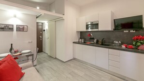 A modern kitchen with white cabinets, a built-in oven, and a flat-screen TV. - notaMi - NotaMi Red Studio (Milan)