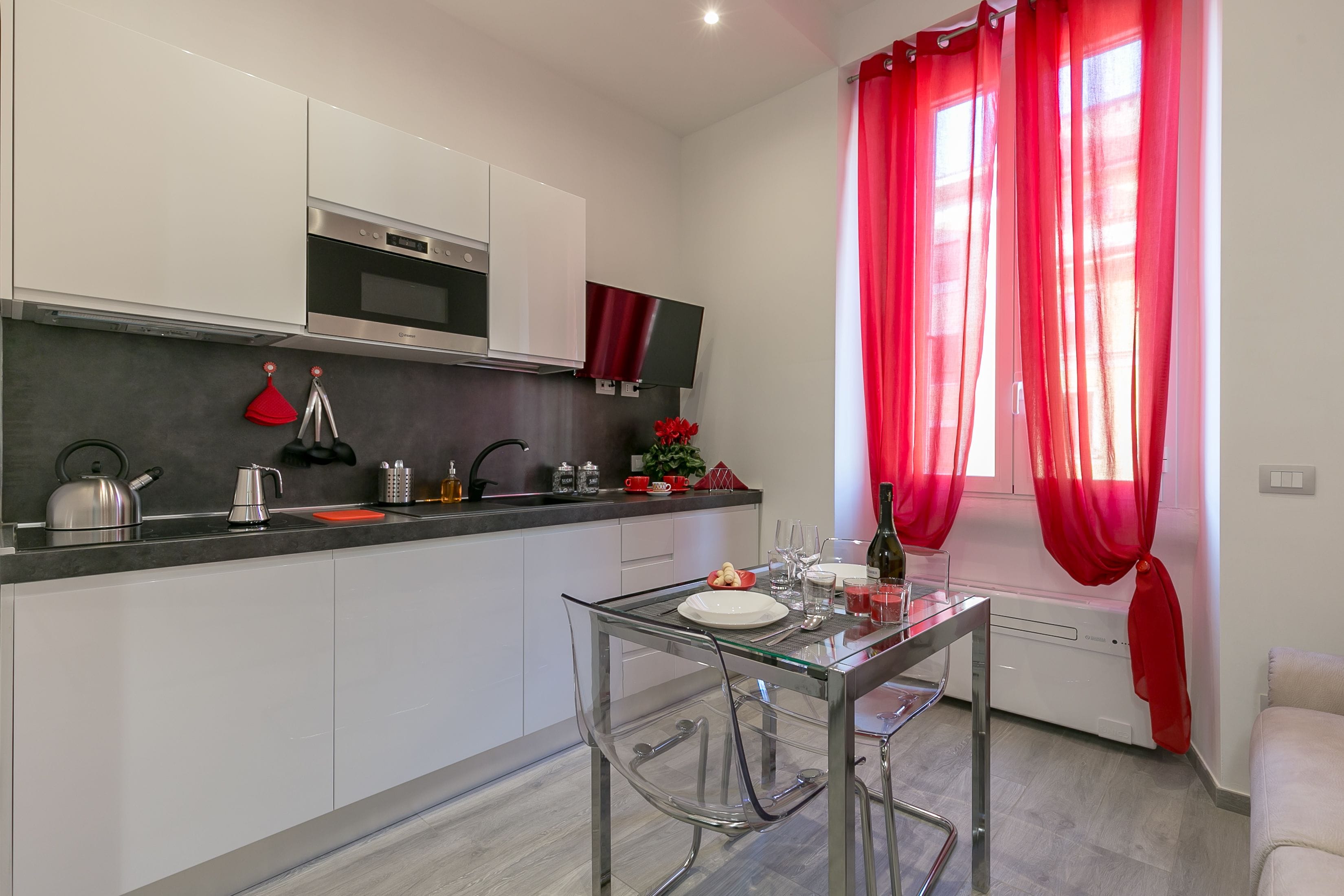 Una cocina moderna con armarios blancos, horno de acero inoxidable y una mesa de comedor de vidrio.