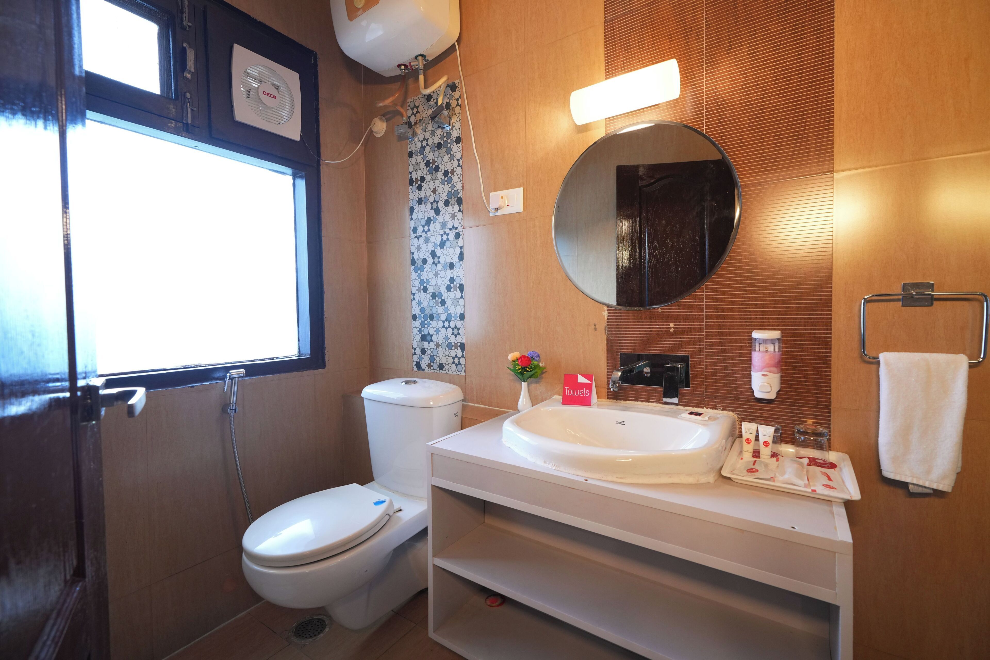 A bathroom with a toilet, sink, mirror, and shower.