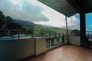 A balcony with a view of green hills and a cloudy sky.