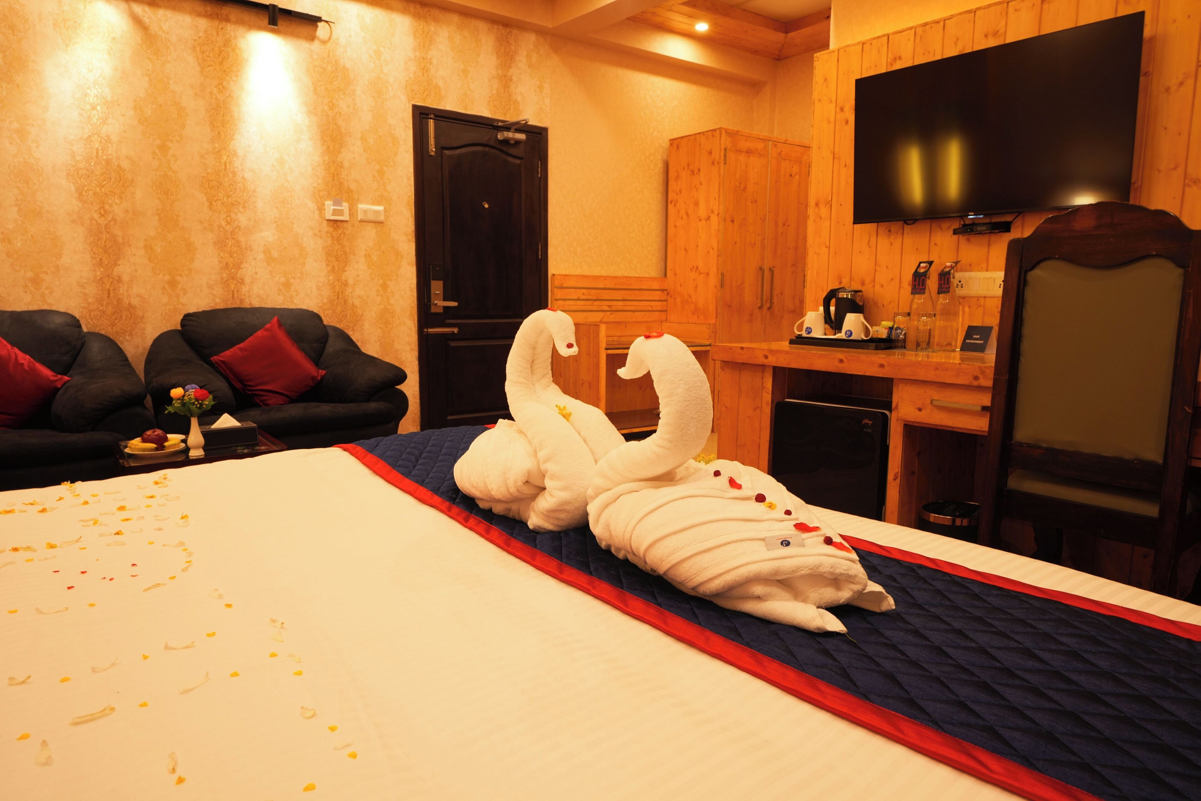 A hotel room with a bed, a sofa, a TV, and a wooden cabinet.