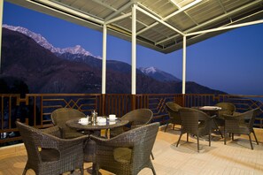 An outdoor seating area with wicker furniture and a view of snow-capped mountains. - Hotel Bella Heights (Dharamshala)