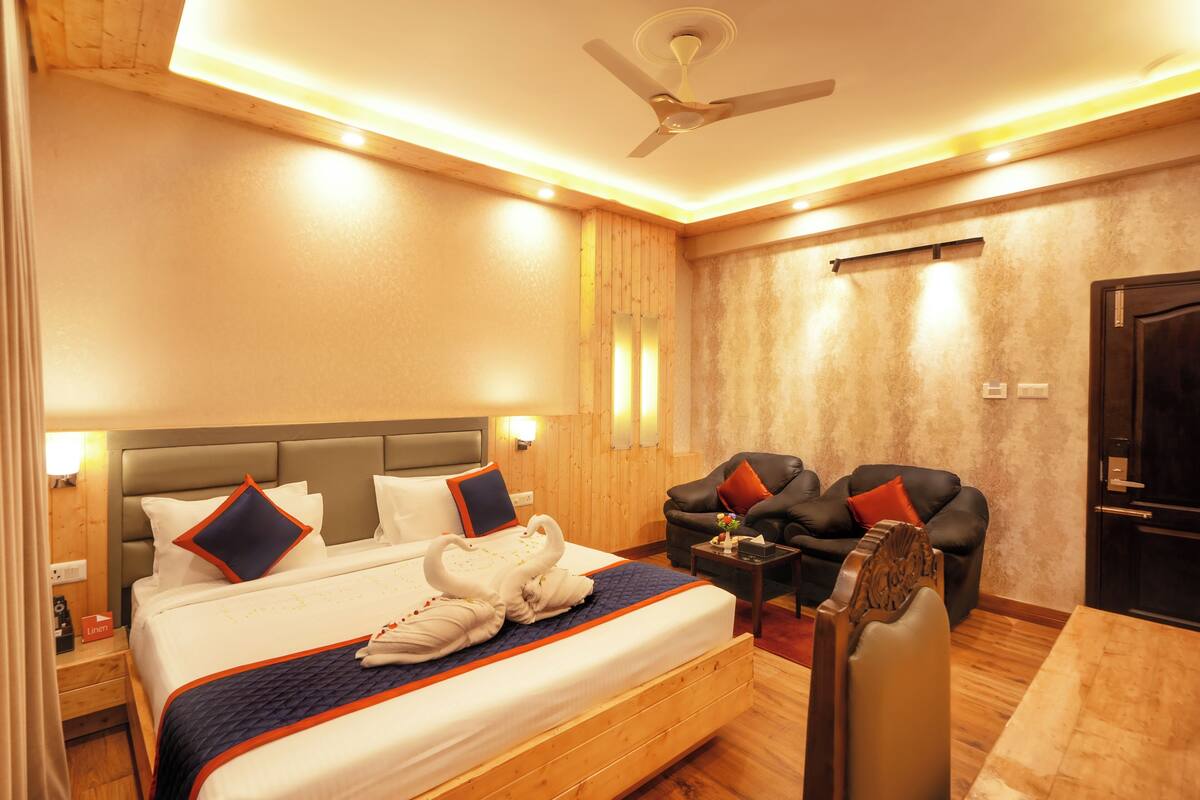 A hotel room with a large bed, a desk, a chair, and a ceiling fan.