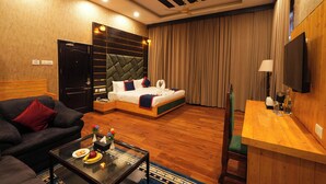 A hotel room with a bed, a sofa, a coffee table, a desk, and a TV. - Hotel Bella Heights (Dharamshala)