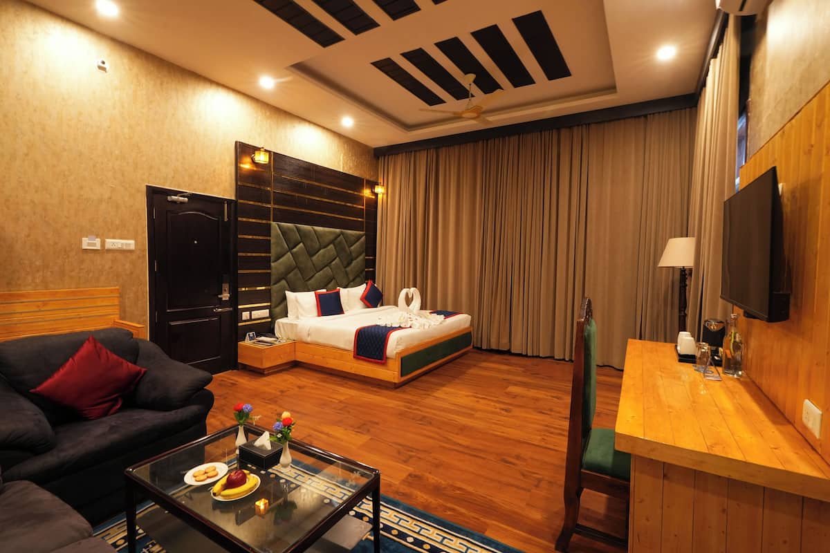A hotel room with a bed, a sofa, a coffee table, a desk, and a TV.