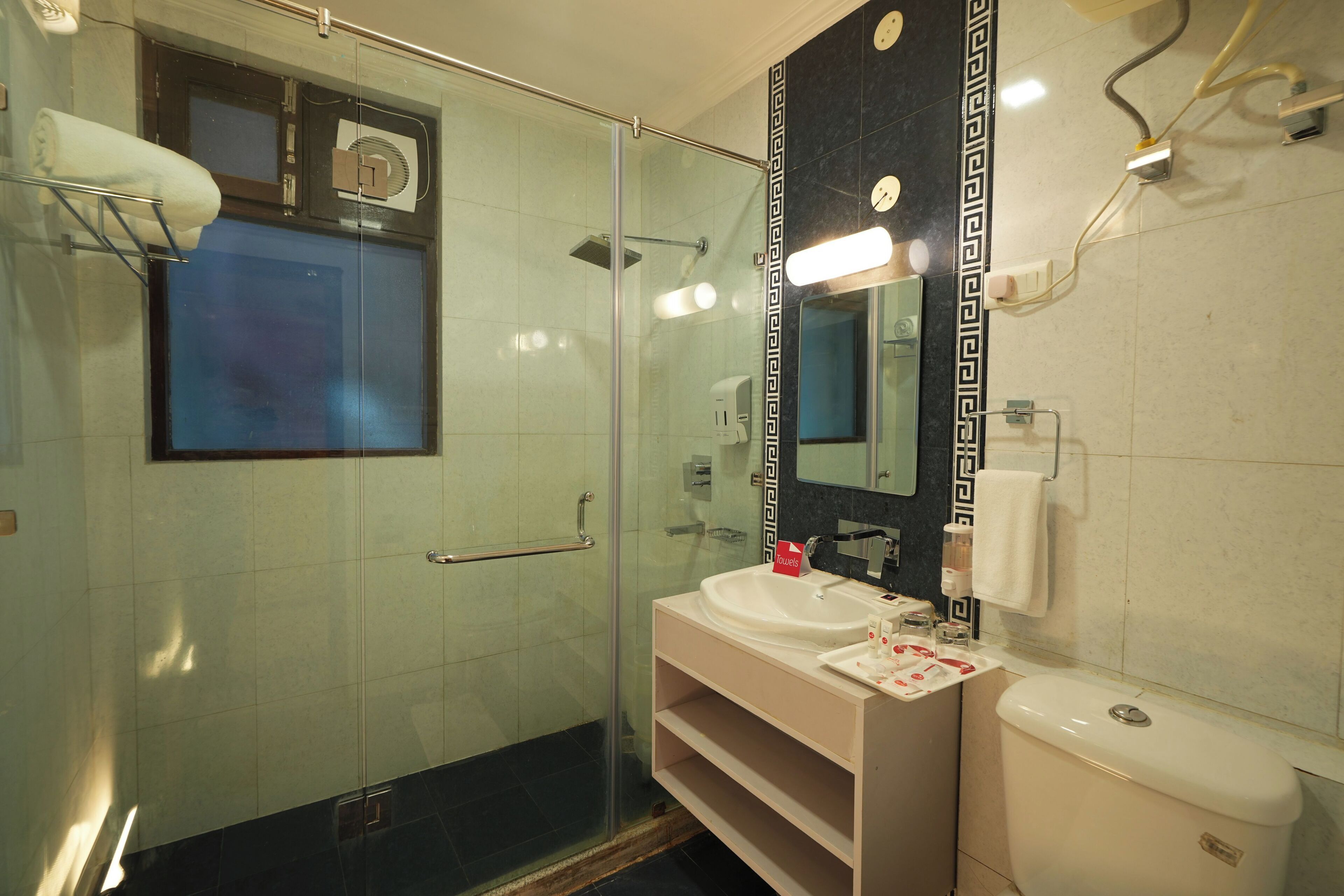 A modern bathroom with a glass-enclosed shower, a white sink, and a large mirror with a decorative frame.
