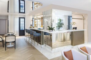 A modern kitchen with a central island, bar stools, and a seating area with a sofa and chairs. - Hotel Parisianer (Paris)