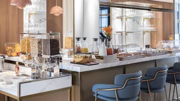Una barra de desayuno con diversas opciones de comida, una estación de café y asientos con taburetes.