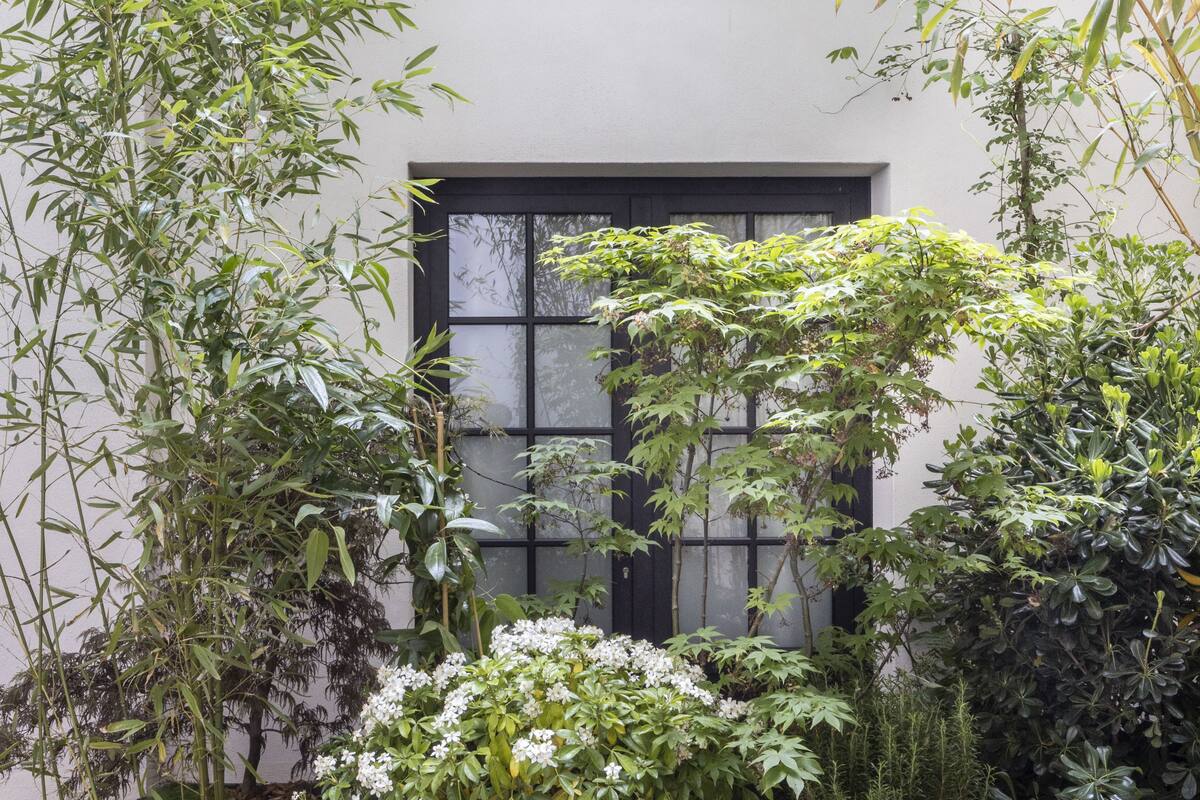 A traditional Japanese-style building with a large window and lush greenery surrounding it.