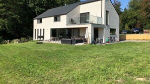 Ein modernes, zweistöckiges Haus mit Flachdach, großen Fenstern und einer überdachten Terrasse.