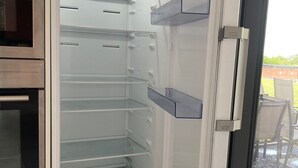 Eine moderne Küche mit Backofen und einem Kühlschrank mit Glastür und mehreren Einlegeböden.