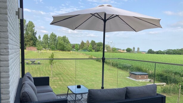 Ein Balkon mit Korbmöbeln, einem Tisch und einem Sonnenschirm.