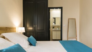 Een hotelkamer met een bed, nachtkastje met een lamp, garderobe, spiegel en een houten trap.