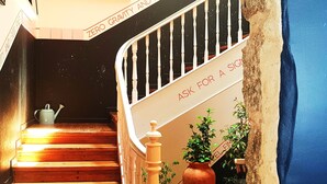 A wooden staircase with a white railing, a potted plant, and a watering can on the landing. - Supernova - Hostel (Porto)