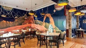 A restaurant with wooden flooring, round tables, and chairs. - Supernova - Hostel (Porto)