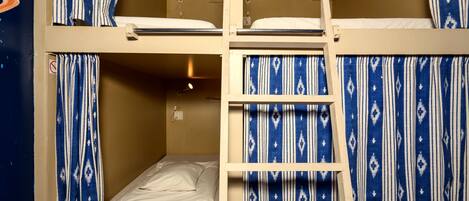 A bunk bed room with a ladder, a small desk, and a wall socket.