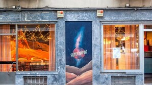 A building facade with large windows, a central advertisement for 'Supernova', and a stone base. - Supernova - Hostel (Porto)