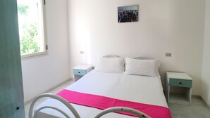 A bedroom with a bed, two bedside tables, a nightstand, a window, and a painting on the wall. - Appartamento Robinia II (Gallipoli)