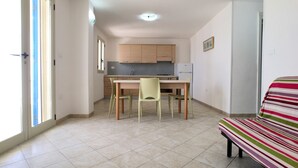Eine kleine Küche mit Essbereich, einem Kühlschrank und einer gestreiften Bank.