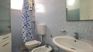 Ein Badezimmer mit Toilette, Bidet, Waschbecken und einer Duschkabine mit Vorhang.