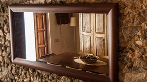 Ein Spiegel mit Holzrahmen spiegelt ein rustikales Interieur wider, mit einem Holztisch, einer Lampe und einer Tür.