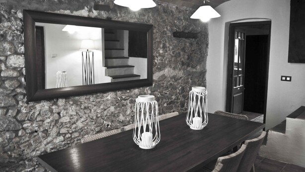 Ein modernes Interieur mit einer Steinwand, einer dunklen Holzbar und zwei weißen, kunstvoll gestalteten Kerzenhaltern.
