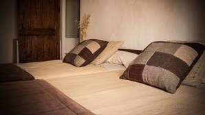Ein Bett mit Holz-Kopfteil, zwei Kissen und einer Vase mit Trockenblumen.