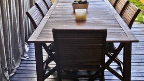 Eine Holzterrasse mit Tisch, Stühlen, einer Kerze und einer Schüssel Tannenzapfen.