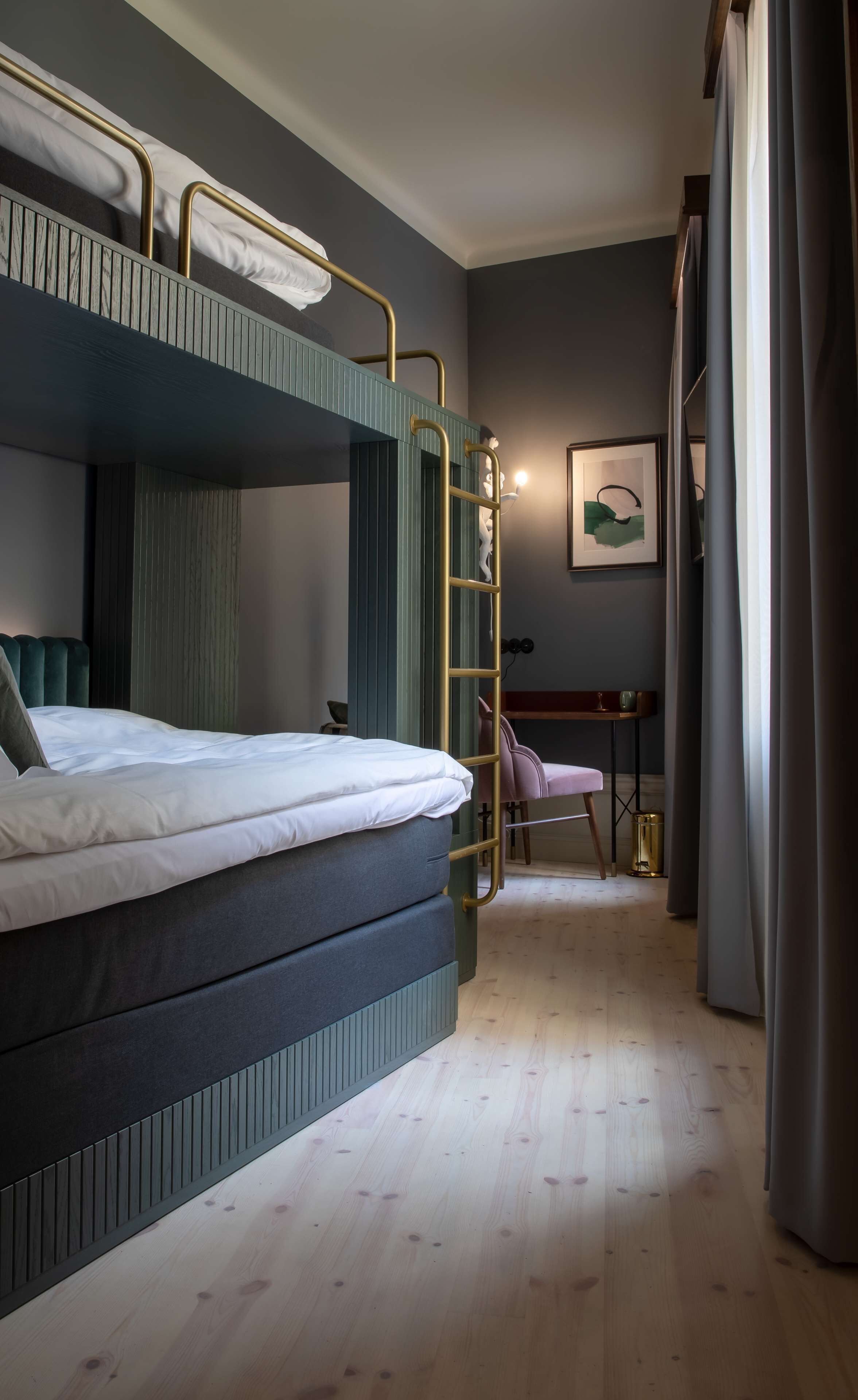 A bunk bed with a ladder, a desk, and a chair in a room with wooden flooring.