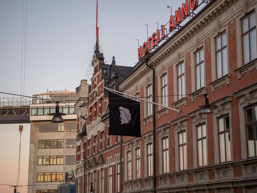 Un edificio histórico con un llamativo letrero rojo que dice "HOTEL AINO".